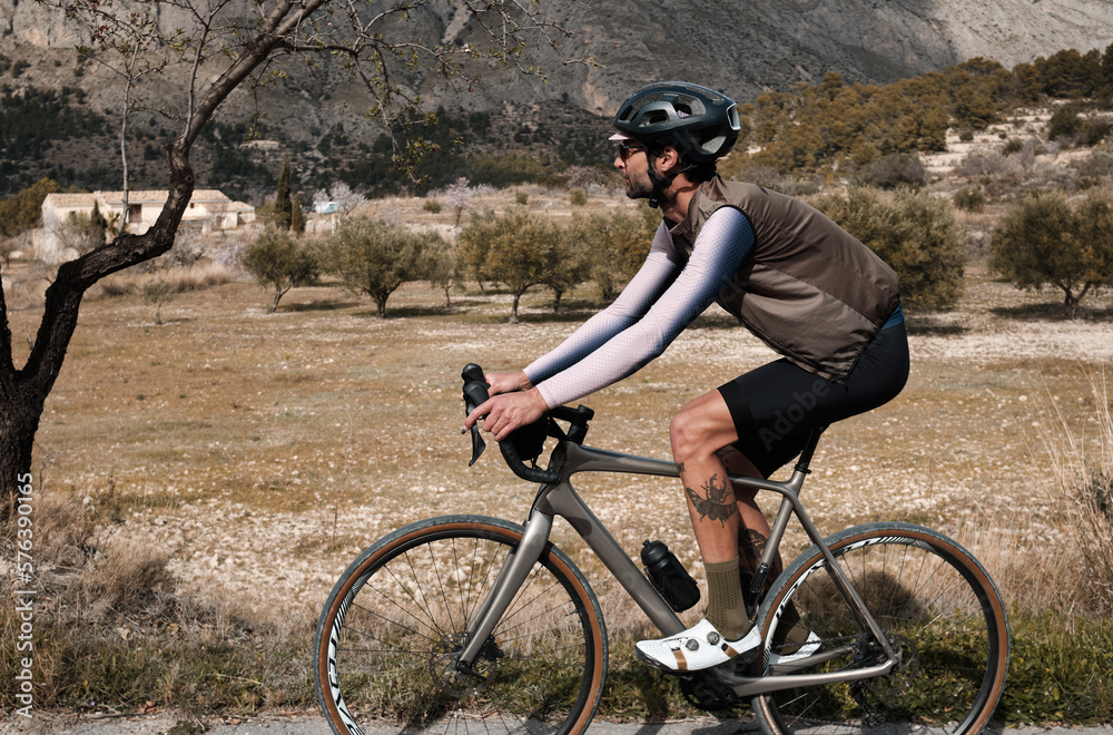 A man on a gravel bike is riding on the road in the hills with a view of the mountains.Sport motivation.Alicante region in Spain