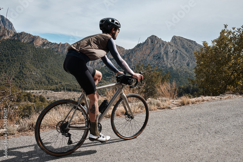 A man on a gravel bike is riding on the road in the hills with a view of the mountains.Sport motivation.Alicante region in Spain