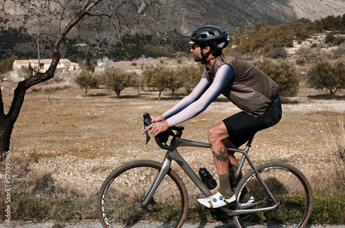 Fototapeta Naklejka Na Ścianę i Meble -  A man on a gravel bike is riding on the road in the hills with a view of the mountains.Sport motivation.Alicante region in Spain