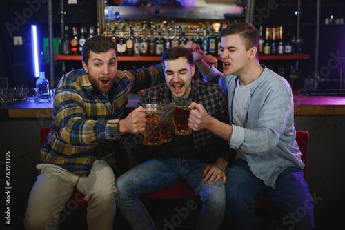 Group of excited friends in beer pub watching sports match
