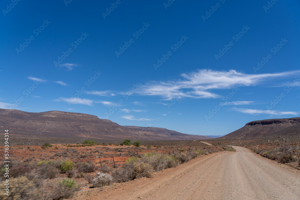 Road in the desert leading into the distance with mountains in the background