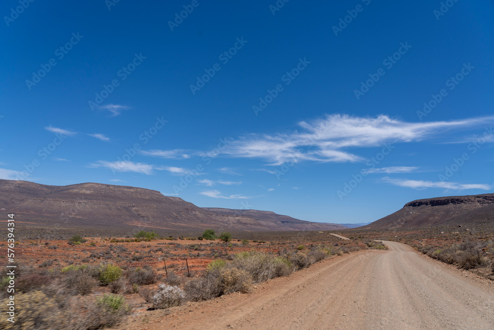 Road in the desert leading into the distance with mountains in the background Road in the desert leading into the distance with mountains in the background