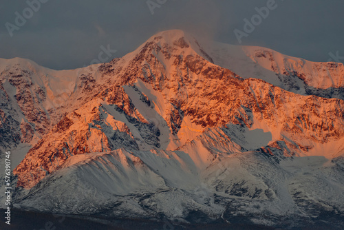 Russia. The South of Western Siberia, the Altai Mountains. The peaks of the North Chui mountain range illuminated by morning sunlight along the Chui tract near the village of Kurai.