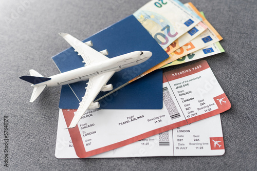 Toy airplane and passport with tickets on gray background, top view