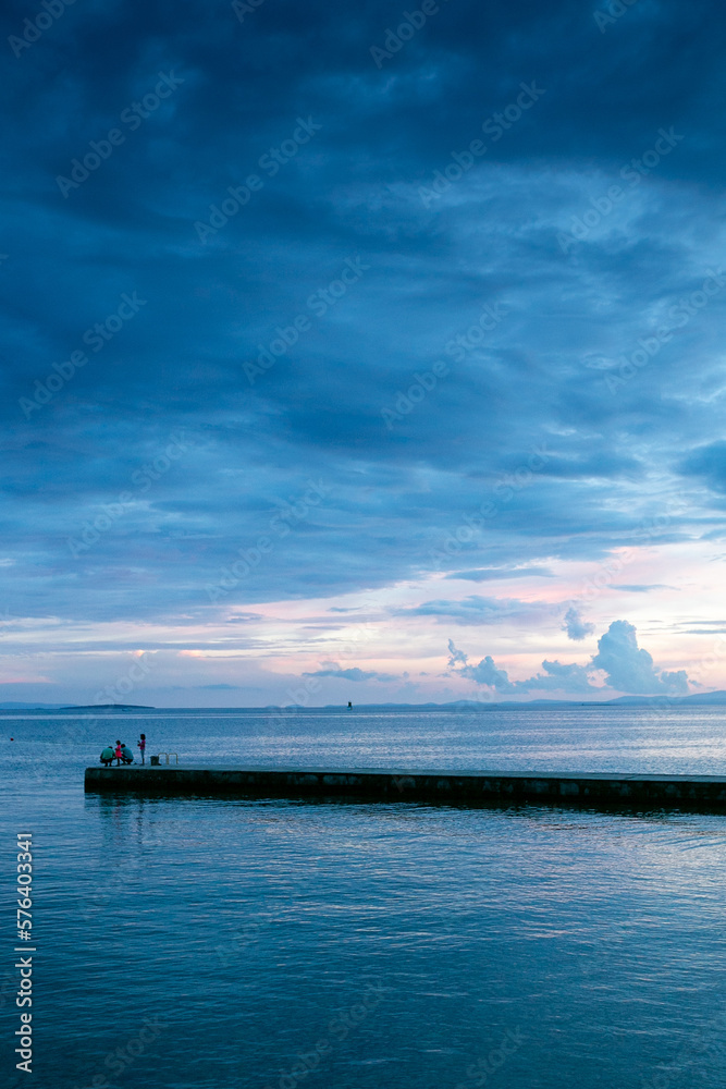 paisaje de atardecer en la costa con una entrada de tierra en el mar y el cielo azulado y violeta