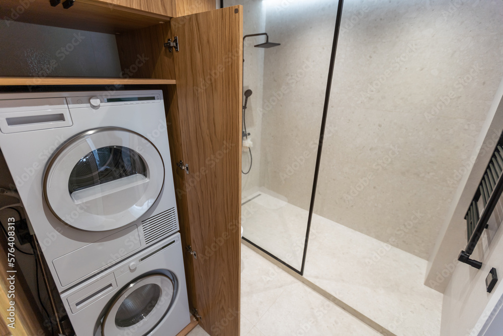 Marble laundry room interior with wooden countertops, a closet and built in washing machines Marble laundry room interior with wooden countertops, a closet and built in washing machines
