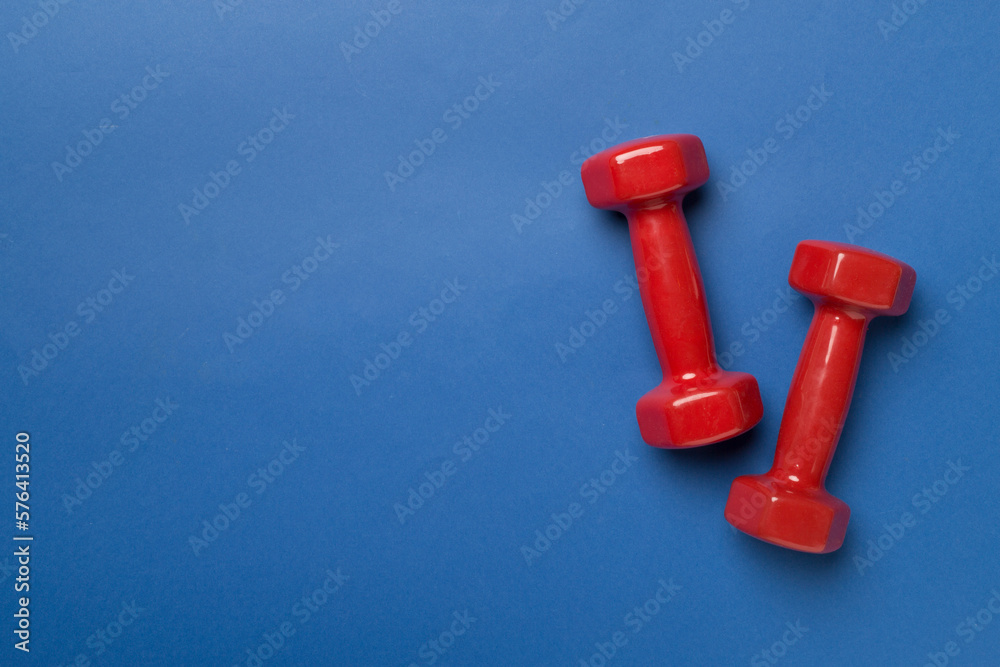 Red dumbbells on color background, top view Red dumbbells on color background, top view