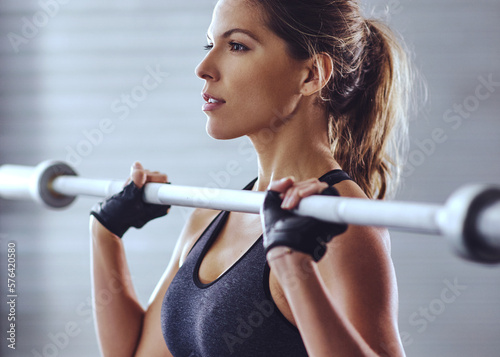 Time to hit the gym. Shot of a young woman working out with weights at the gym.