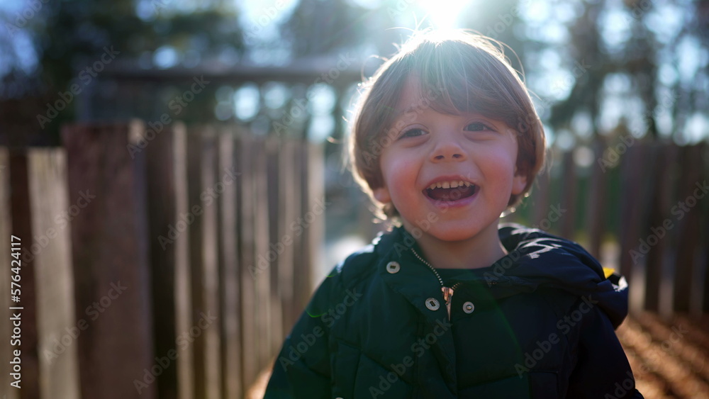 One adorable happy child laughing and smiling outside in sunny autumn day. Portrait of a joyful handsome kid authentic real life smile and laugh