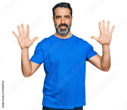 Middle aged man with beard wearing casual blue t shirt showing and pointing up with fingers number ten while smiling confident and happy. © Krakenimages.com