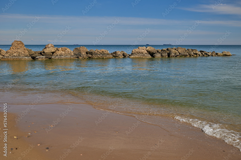 Blue sea, blue sky with clouds and high stones