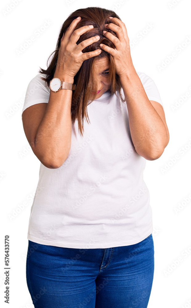 Middle age latin woman wearing casual white tshirt suffering from headache desperate and stressed because pain and migraine. hands on head. Middle age latin woman wearing casual white tshirt suffering from headache desperate and stressed because pain and migraine. hands on head.