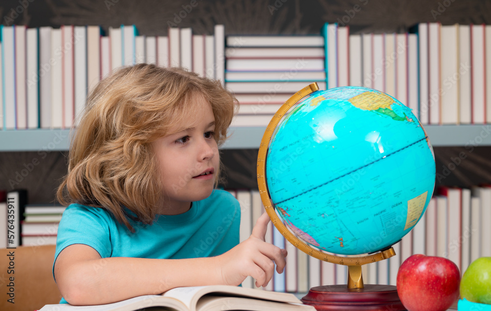 School boy looking at globe in library, geography lesson. School child ...