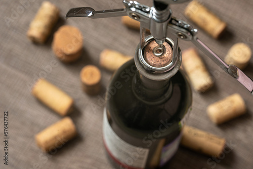 Opening a bottle of wine with a corkscrew.