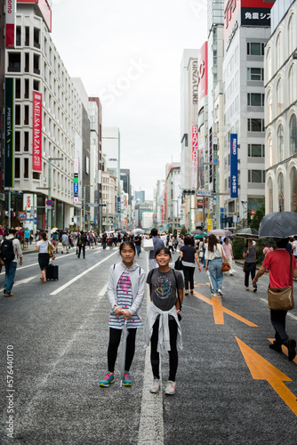 Two asian girls standing in middle of street in Ginza Japan