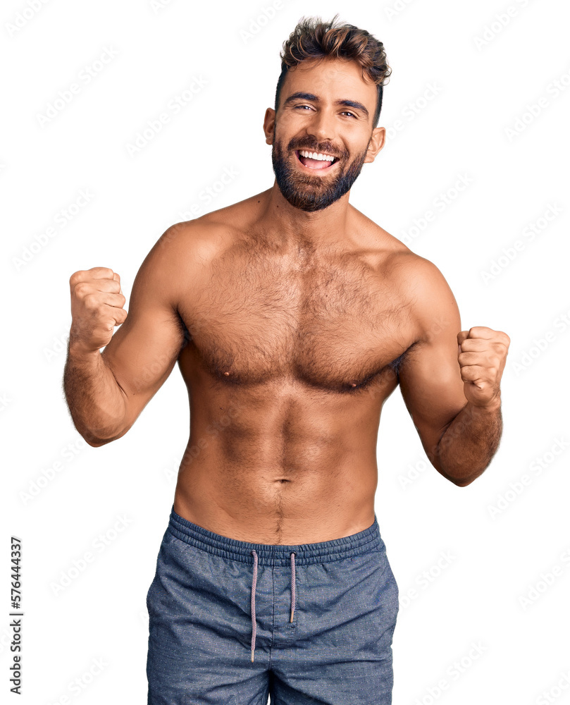 Young hispanic man wearing swimwear shirtless celebrating surprised and amazed for success with arms raised and open eyes. winner concept. Young hispanic man wearing swimwear shirtless celebrating surprised and amazed for success with arms raised and open eyes. winner concept.