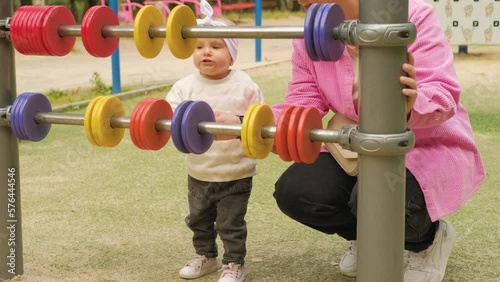 A mother spends time with her young child on the playground in the park