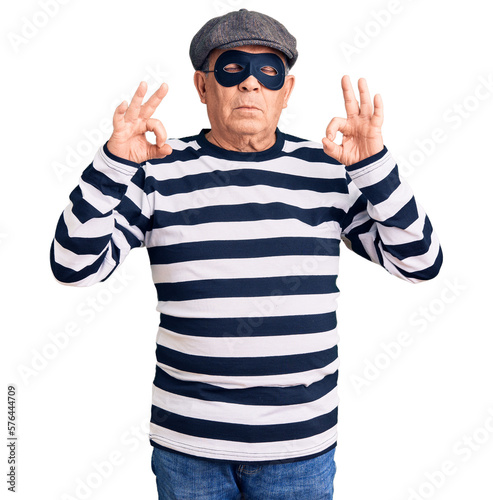 Senior handsome man wearing burglar mask and t-shirt relaxed and smiling with eyes closed doing meditation gesture with fingers. yoga concept.