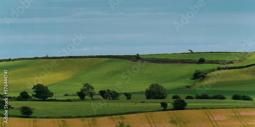 Picturesque agricultural landscape. Green hills under a blue sky. Hilly terrain in the south of Ireland, nature.