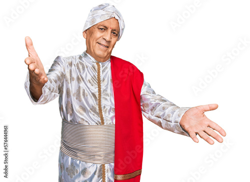 Photography Senior hispanic man wearing tradition sherwani saree clothes looking at the camera smiling with open arms for hug