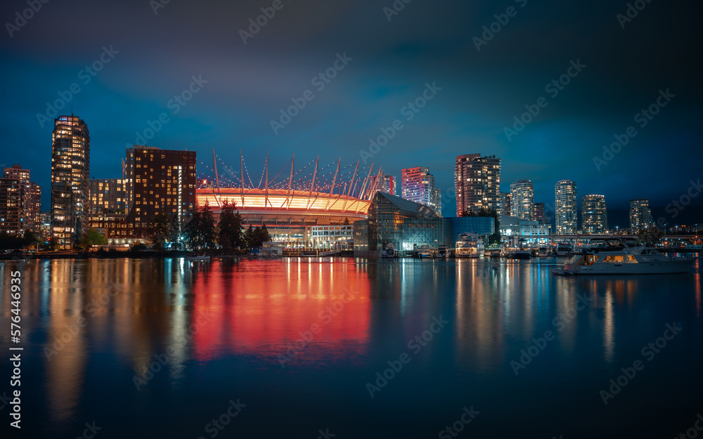 Long exposure night photograph of the illuminated city of Vancouver, Canada, and its reflection in the water.