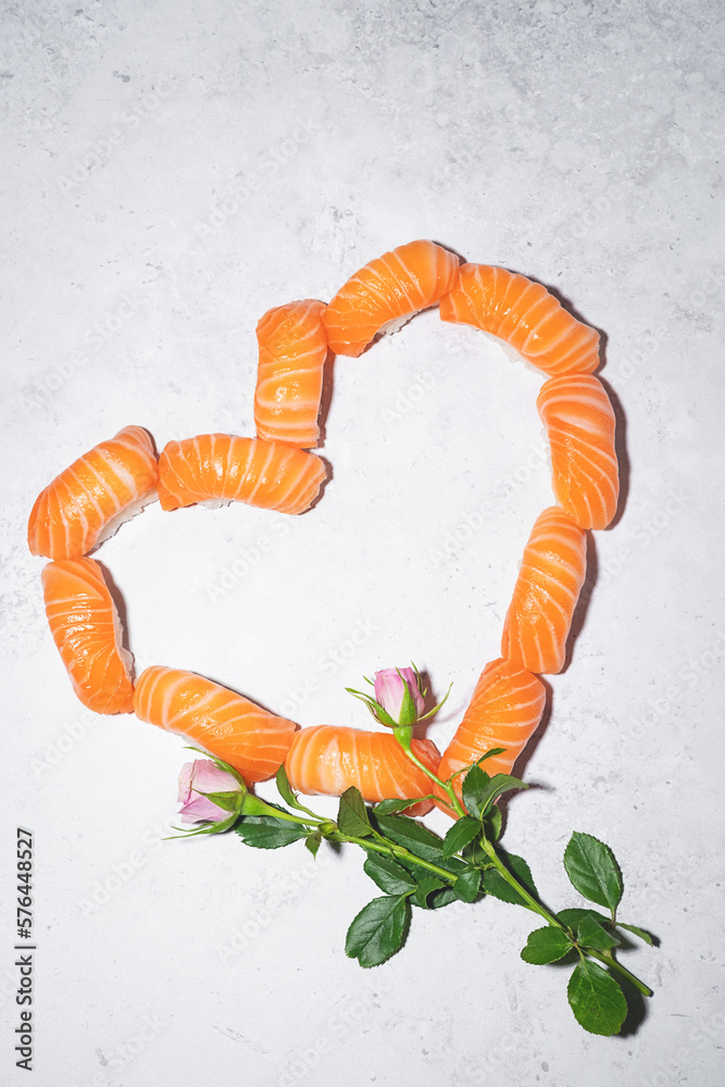 Sushi heart with flowers on grey background. Love sushi. Salmon nigiri with blooming roses. Women's day, Valentines day and spring celebration. Romantic dinner date. Creative Japanese set. Vertical