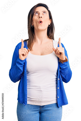 Young beautiful woman wearing casual clothes amazed and surprised looking up and pointing with fingers and raised arms.