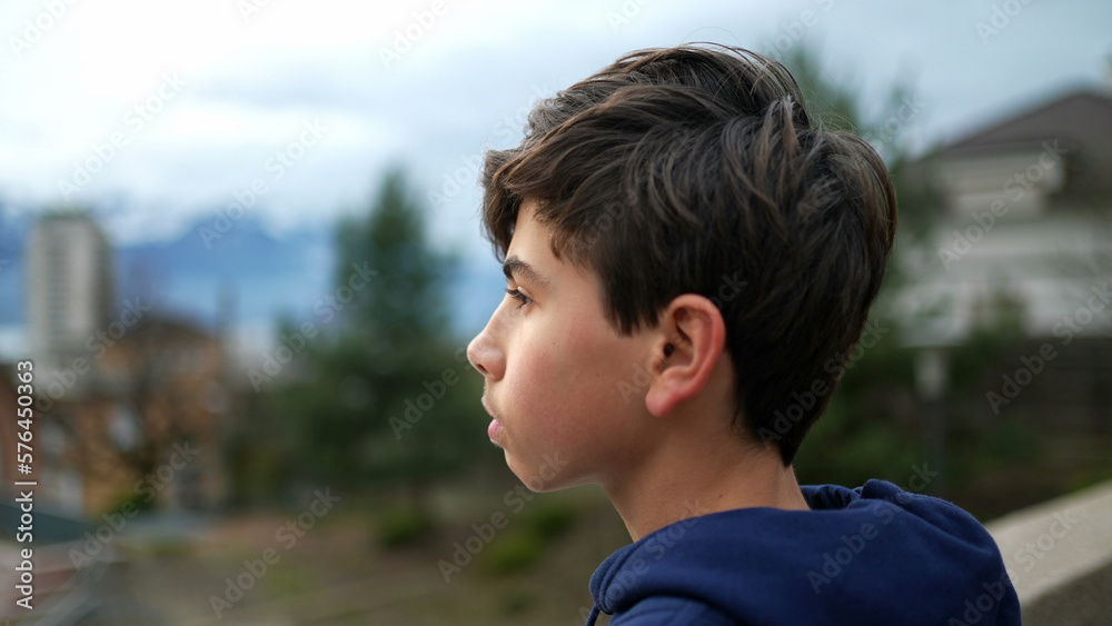 One thoughtful teenager boy standing outside. Closeup face of contemplative young male kid. Person looking at horizon with pensive expression One thoughtful teenager boy standing outside. Closeup face of contemplative young male kid. Person looking at horizon with pensive expression