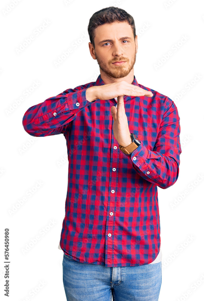 Handsome young man with bear wearing casual shirt doing time out gesture with hands, frustrated and serious face Handsome young man with bear wearing casual shirt doing time out gesture with hands, frustrated and serious face