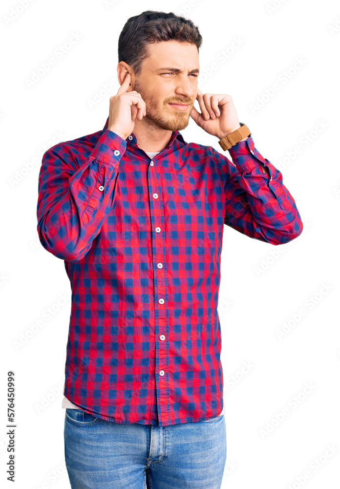 Handsome young man with bear wearing casual shirt covering ears with fingers with annoyed expression for the noise of loud music. deaf concept. Handsome young man with bear wearing casual shirt covering ears with fingers with annoyed expression for the noise of loud music. deaf concept.
