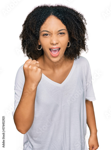 Young african american girl wearing casual clothes angry and mad raising fist frustrated and furious while shouting with anger. rage and aggressive concept.