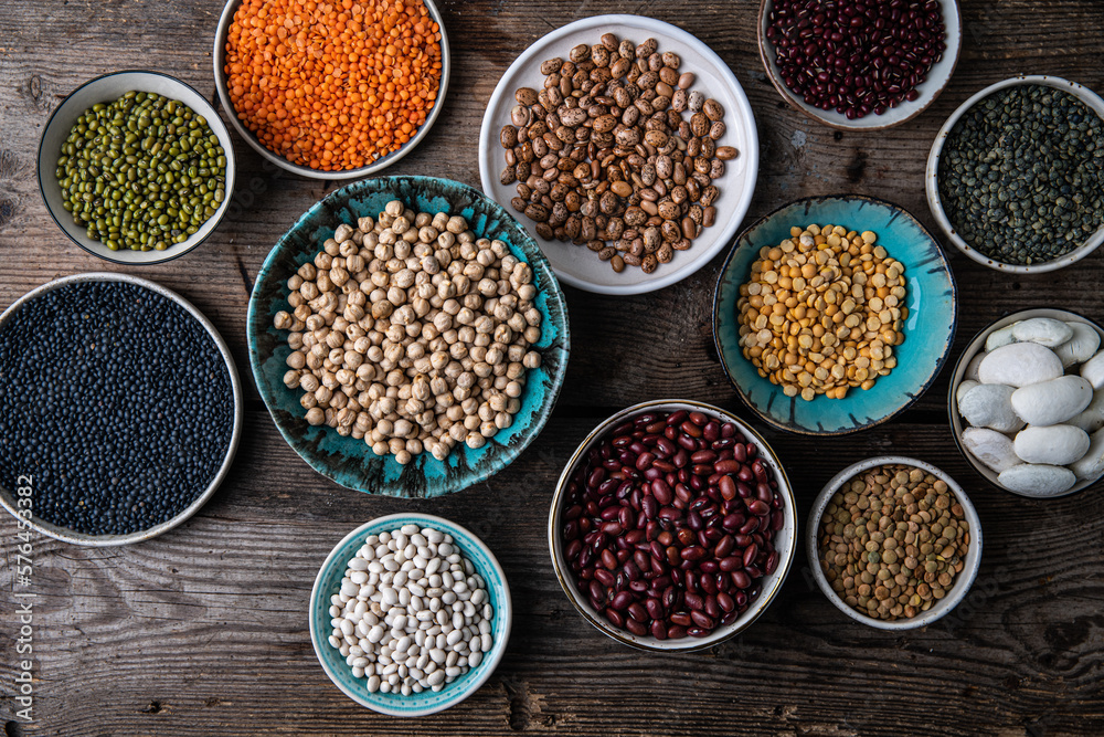 Different legumes (lentils, beans, chickpeas, mung, peas) in bowls and plates on wooden background. Different legumes (lentils, beans, chickpeas, mung, peas) in bowls and plates on wooden background.