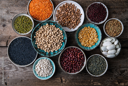 Print op canvas Different legumes (lentils, beans, chickpeas, mung, peas) in bowls and plates on wooden background