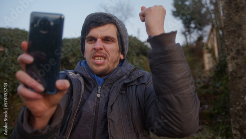 Man in Natural Green Scenery Uses Phone and Reacts with Joy to App Concept