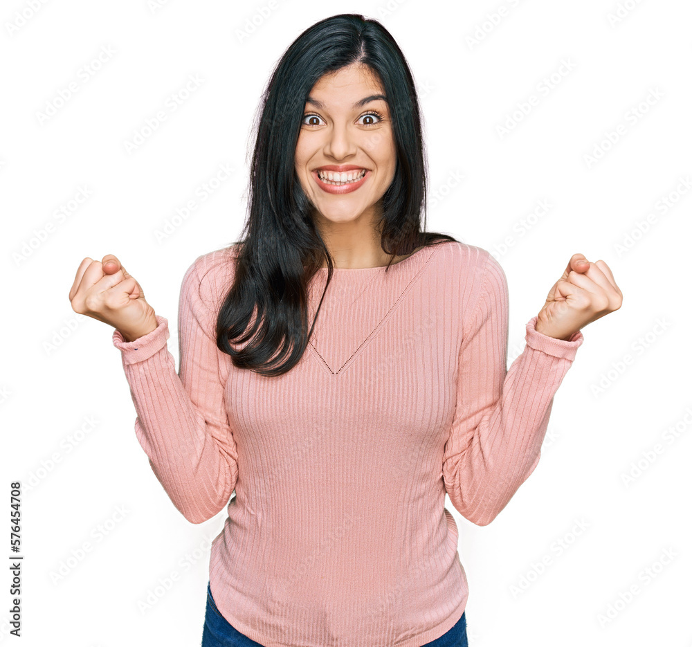 Young hispanic woman wearing casual clothes celebrating surprised and amazed for success with arms raised and open eyes. winner concept. Young hispanic woman wearing casual clothes celebrating surprised and amazed for success with arms raised and open eyes. winner concept.