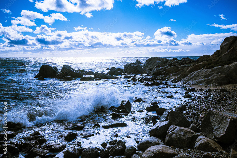 Obraz premium Waves of the Mediterranean Sea which with foam and splashes break against huge stones on the shore, Cagliari, Sardinia, Italy