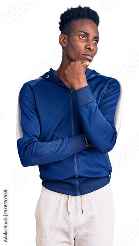Young african american man wearing sportswear with hand on chin thinking about question, pensive expression. smiling with thoughtful face. doubt concept.