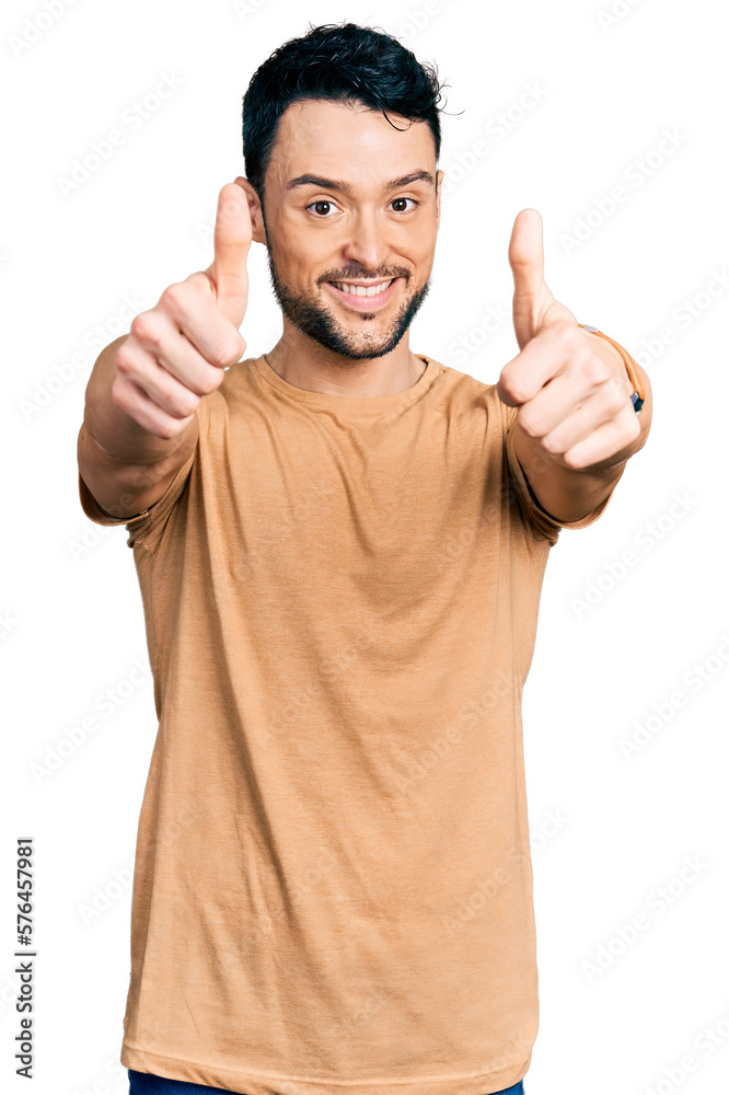 Hispanic man with beard wearing casual t shirt approving doing positive gesture with hand, thumbs up smiling and happy for success. winner gesture. Hispanic man with beard wearing casual t shirt approving doing positive gesture with hand, thumbs up smiling and happy for success. winner gesture.