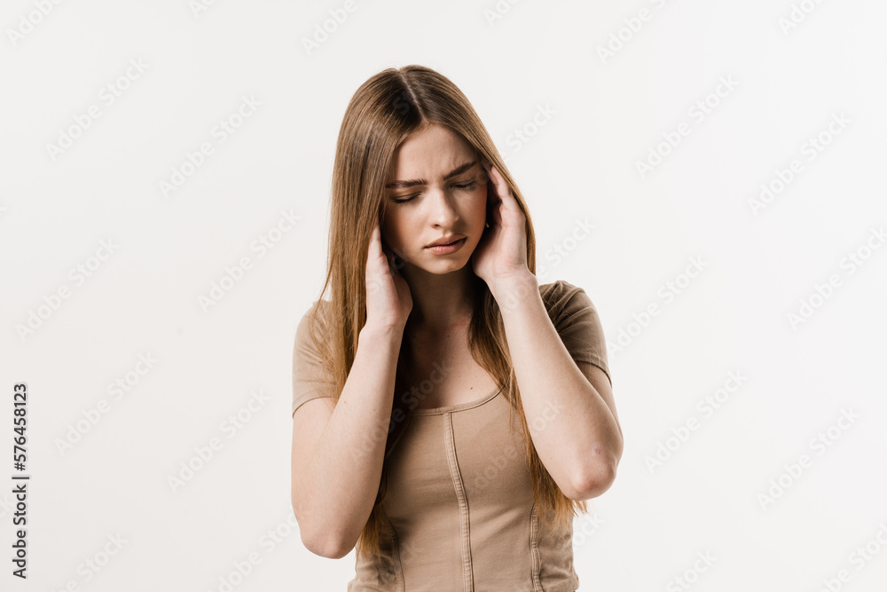 Migraine is a strong headache of girl isolated on white background. Overstressed young woman touches her head because of pain. Depression of attractive girl.