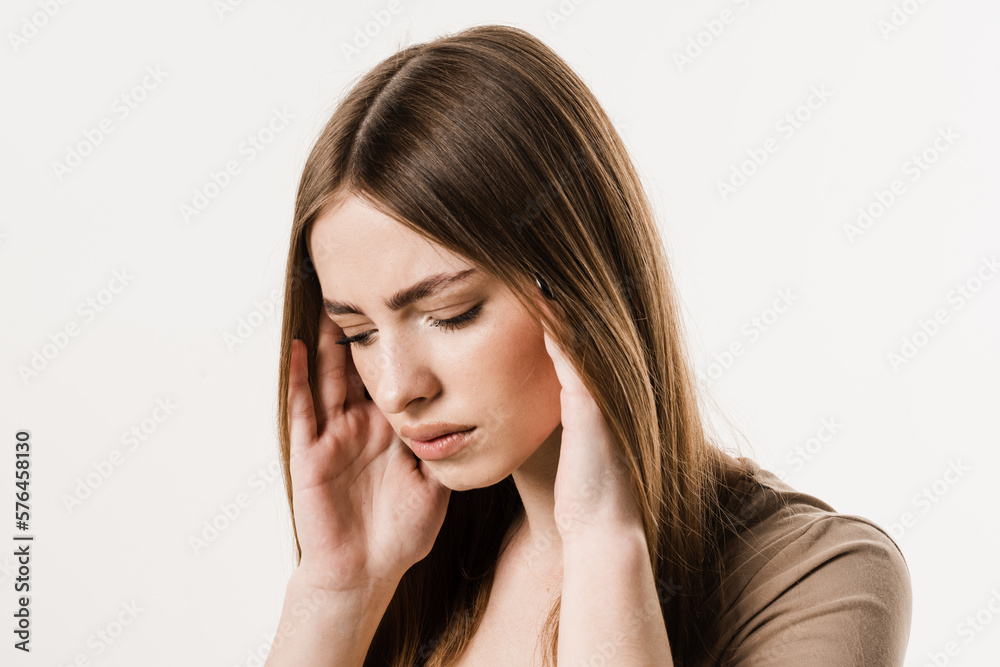 Migraine is a strong headache of girl isolated on white background. Overstressed young woman touches her head because of pain. Depression of attractive girl. Migraine is a strong headache of girl isolated on white background. Overstressed young woman touches her head because of pain. Depression of attractive girl.