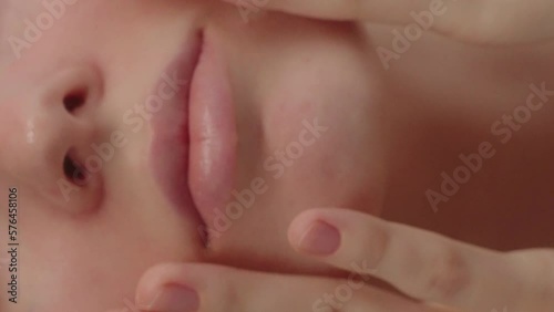 Extreme closeup feminine lips and chin applying anti aging cream photo