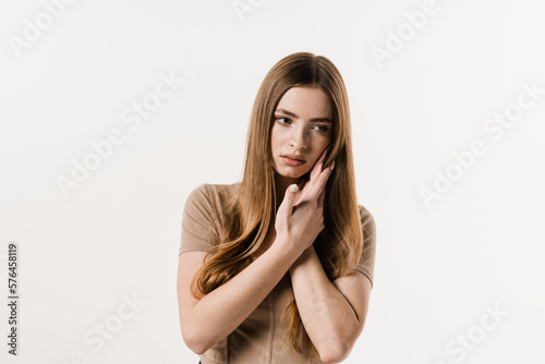 Girl with tooth decay, infection or injury to the tooth or gums on white background. Girl is touching cheek and feeling toothache pain and discomfort of tooth.