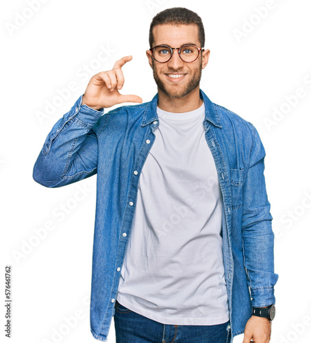 Young caucasian man wearing casual clothes smiling and confident gesturing with hand doing small size sign with fingers looking and the camera. measure concept.