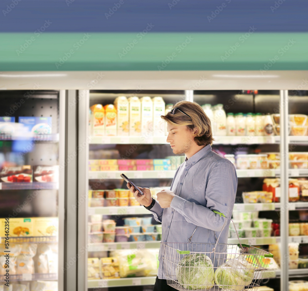  Man choosing frozen food from a supermarket freezer., reading product information