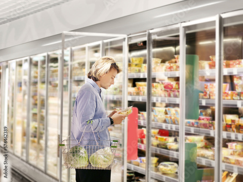 Man choosing frozen food from a supermarket freezer., reading product information