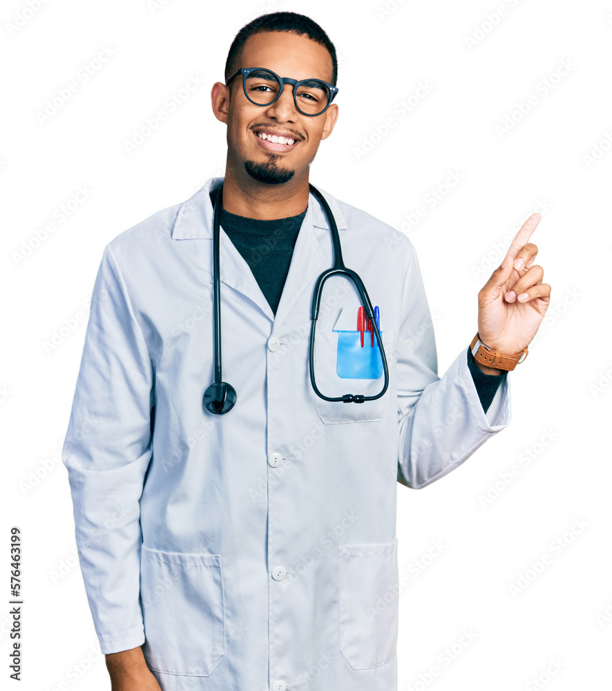 Young african american man wearing doctor uniform and stethoscope with a big smile on face, pointing with hand finger to the side looking at the camera. Young african american man wearing doctor uniform and stethoscope with a big smile on face, pointing with hand finger to the side looking at the camera.