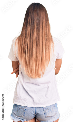 Beautiful caucasian woman wearing casual white tshirt standing backwards looking away with crossed arms