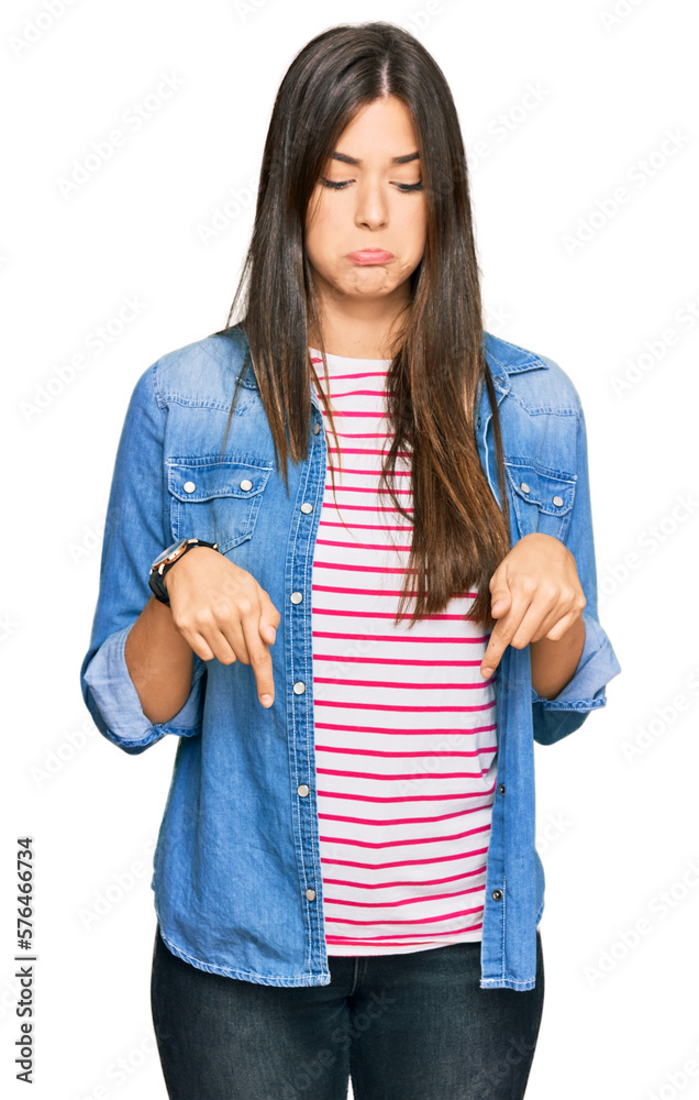Young brunette woman wearing casual clothes pointing down looking sad and upset, indicating direction with fingers, unhappy and depressed. Young brunette woman wearing casual clothes pointing down looking sad and upset, indicating direction with fingers, unhappy and depressed.