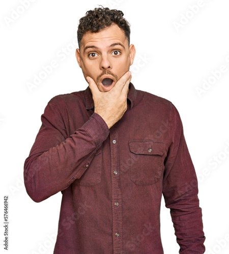 Young hispanic man wearing casual clothes looking fascinated with disbelief, surprise and amazed expression with hands on chin