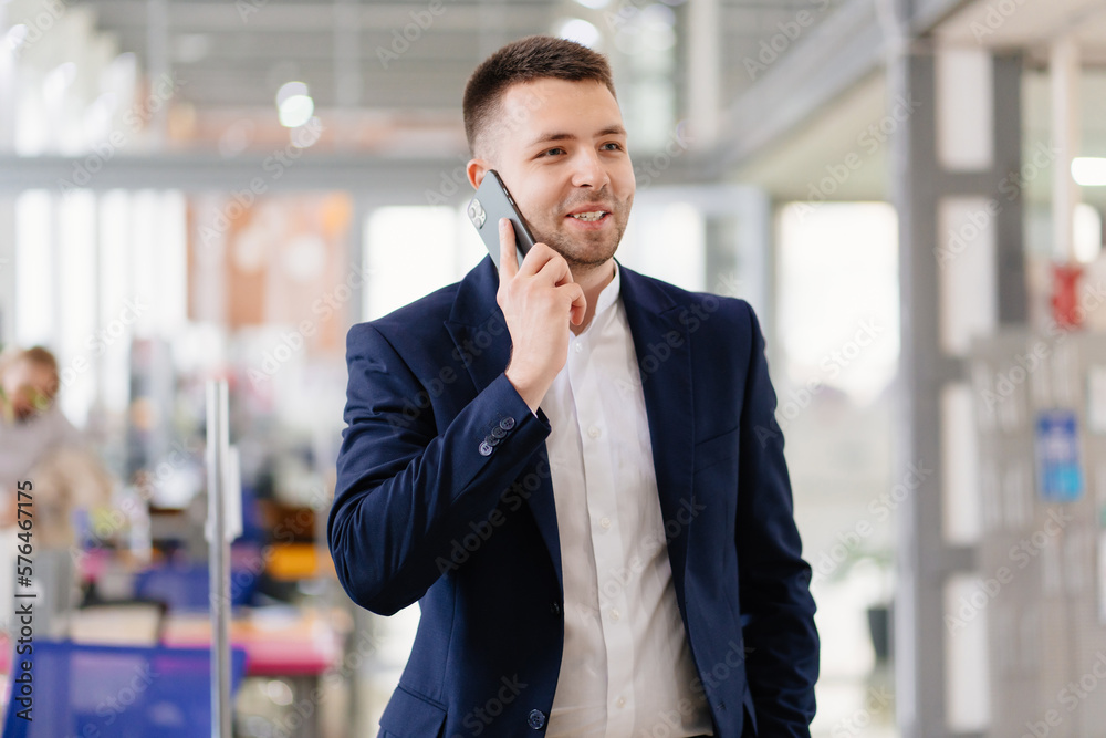 a man in a blue business suit talks on the phone in the coworking office. a man in a blue business suit talks on the phone in the coworking office.